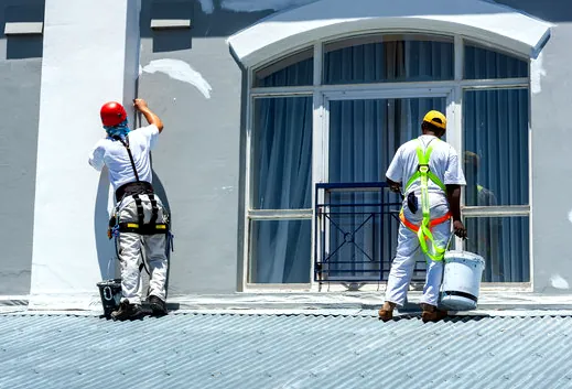 Two painters in harnesses repainting a commercial facade in Gardena